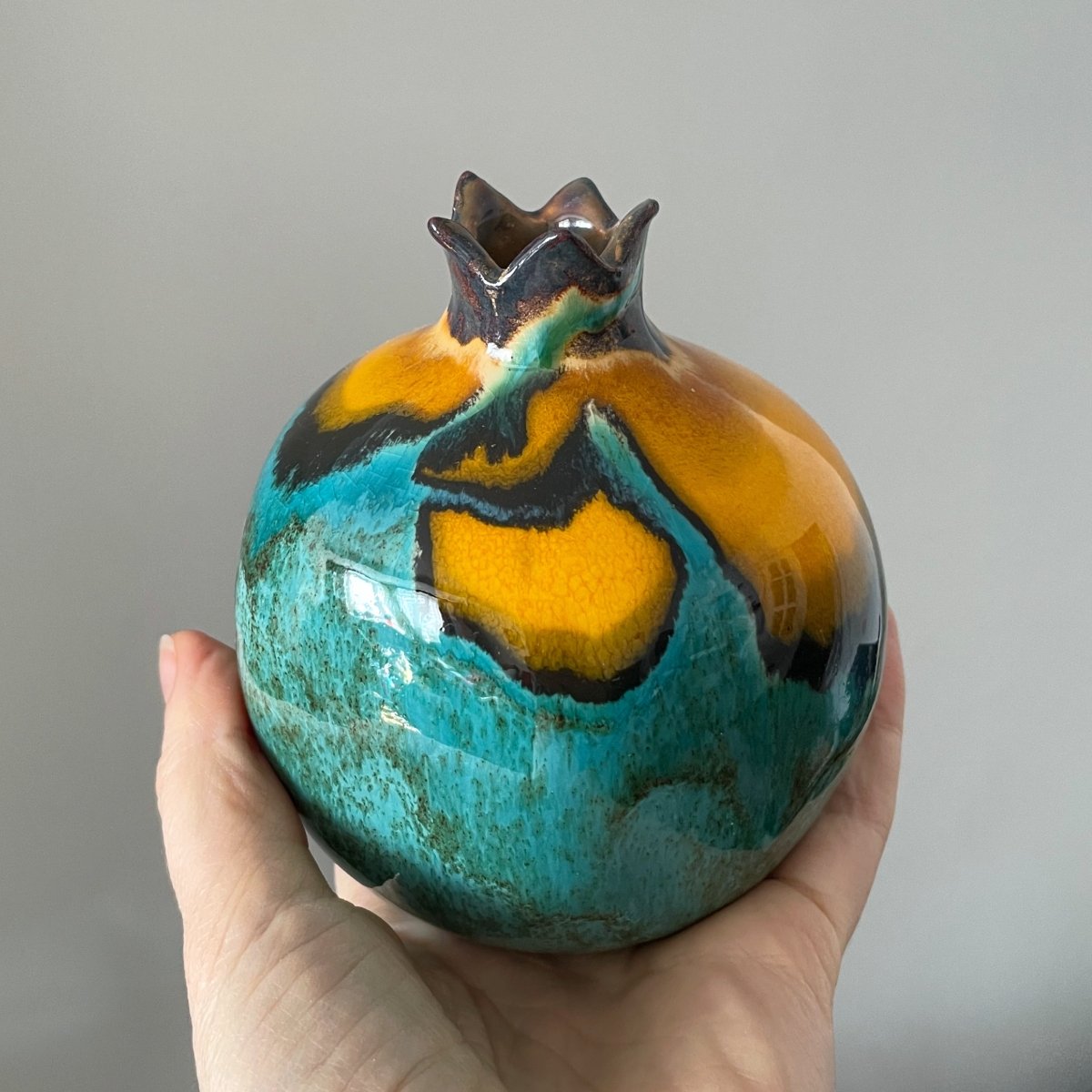 Handcrafted pottery pomegranate with expressive yellow detail, unique ceramic home decor piece